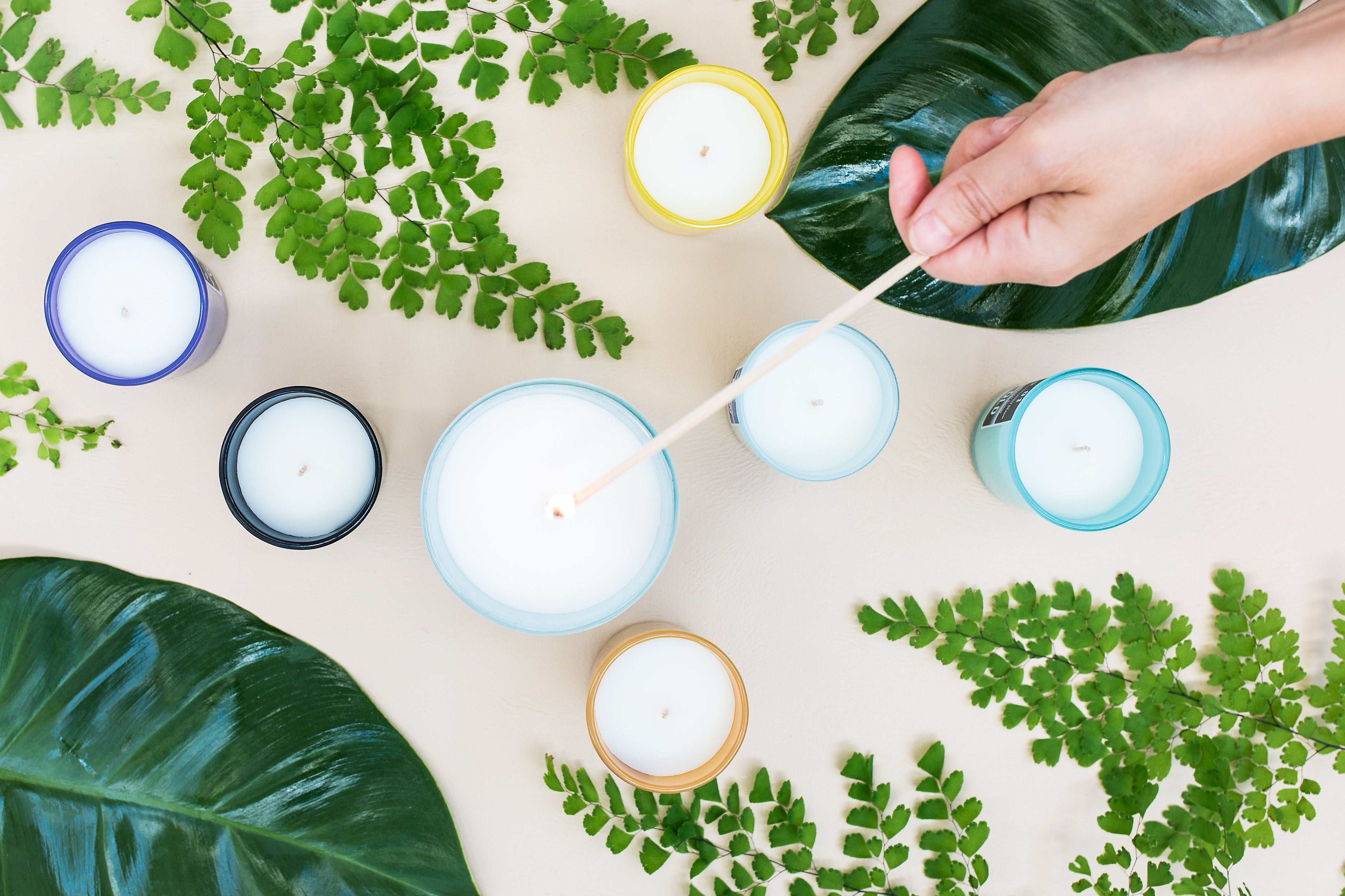 Candles of various sizes with leaves around it 