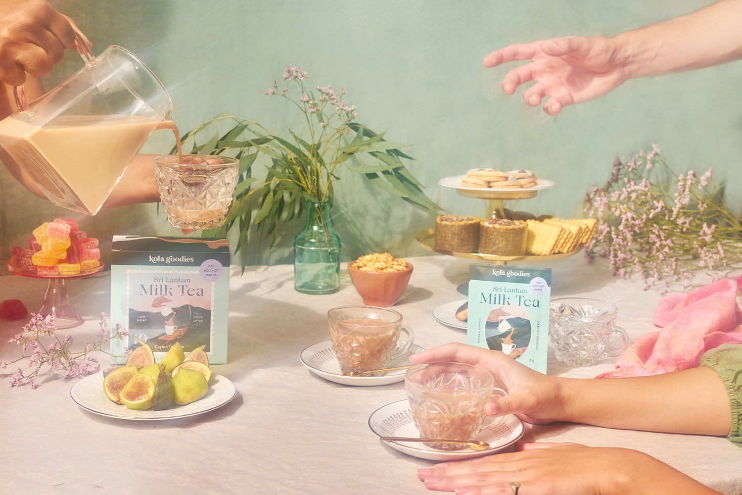 Kola Goodies' Sri Lankan milk tea displayed in a professional photo shoot, with the tea being poured and served to several people